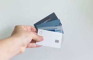 A hand holding four credit cards.